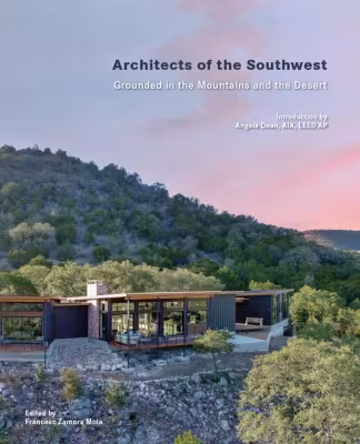 Modern house in forested hillside at sunset.