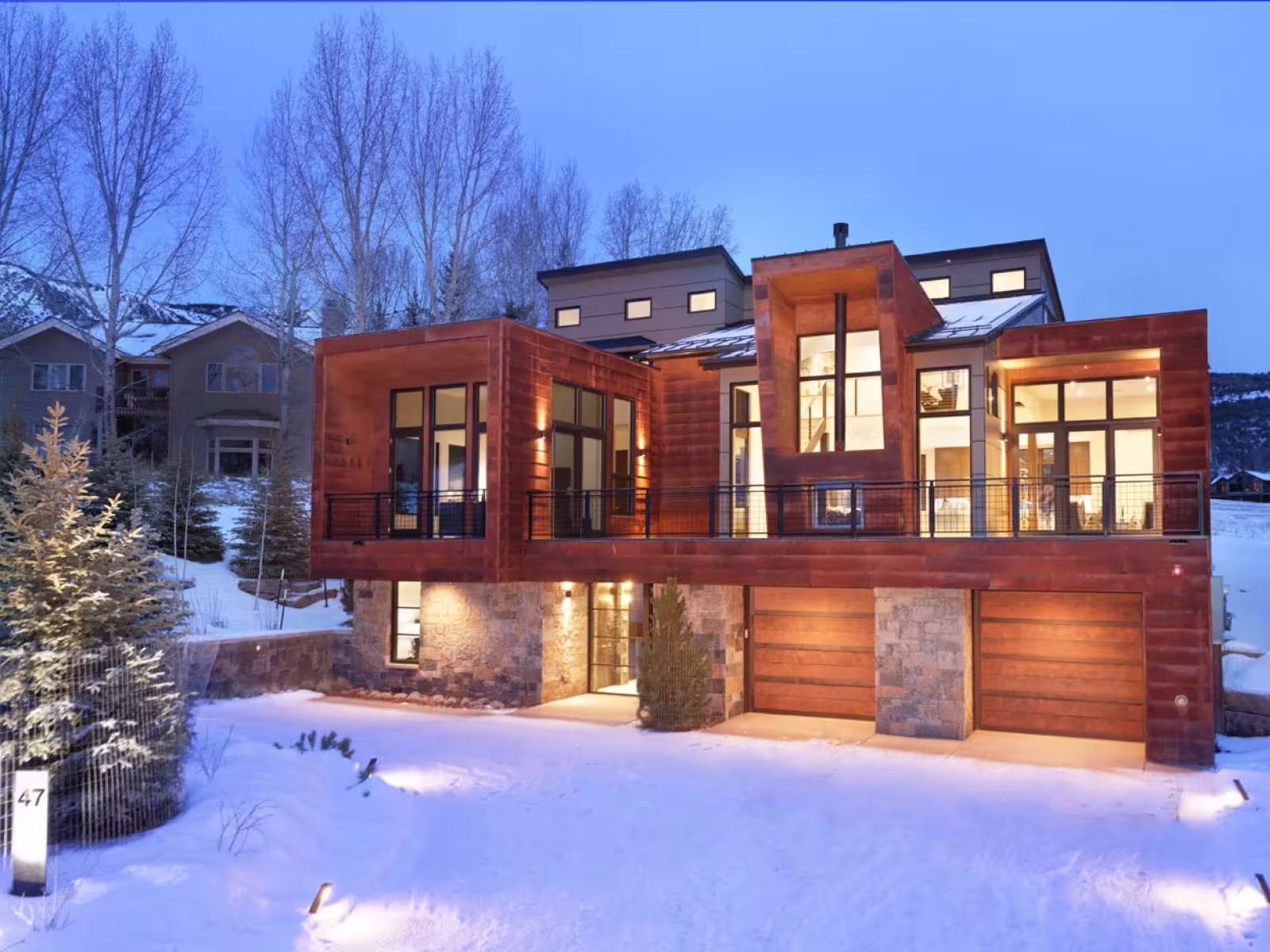 Modern wooden house in snowy landscape at dusk.