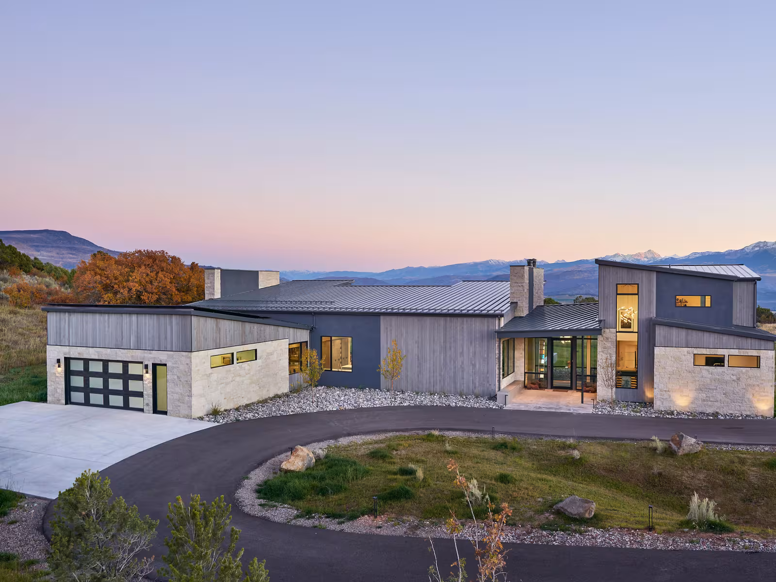 Modern house at sunset, mountains in background.