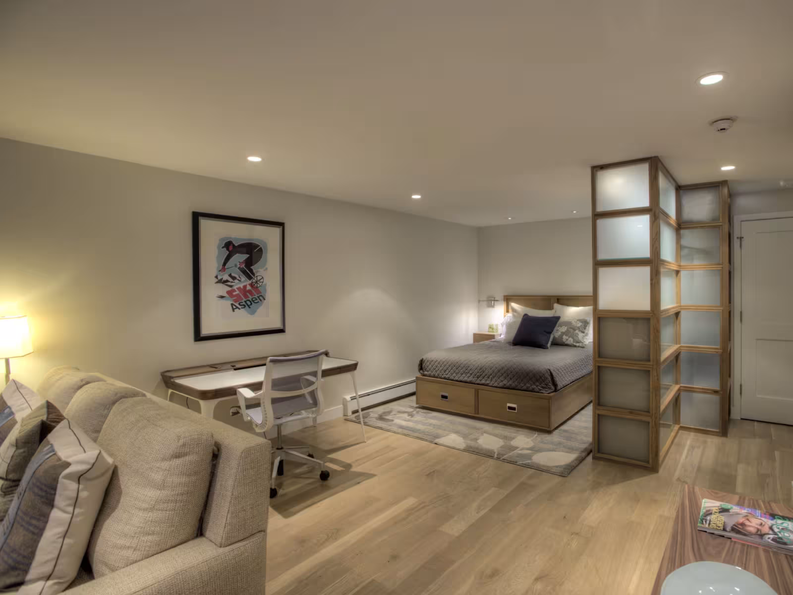 Stylish bedroom with a desk, sofa, and artwork on the wall.