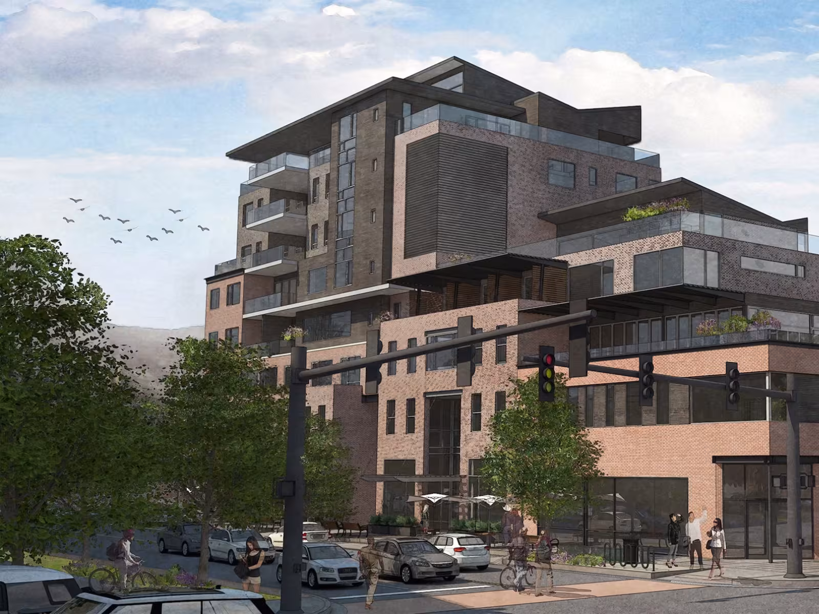 Modern multi-storey building at busy intersection, cars and trees nearby.